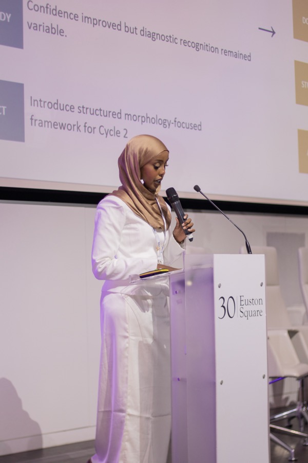 A delegate presents her work from the lectern at ESMC 2026